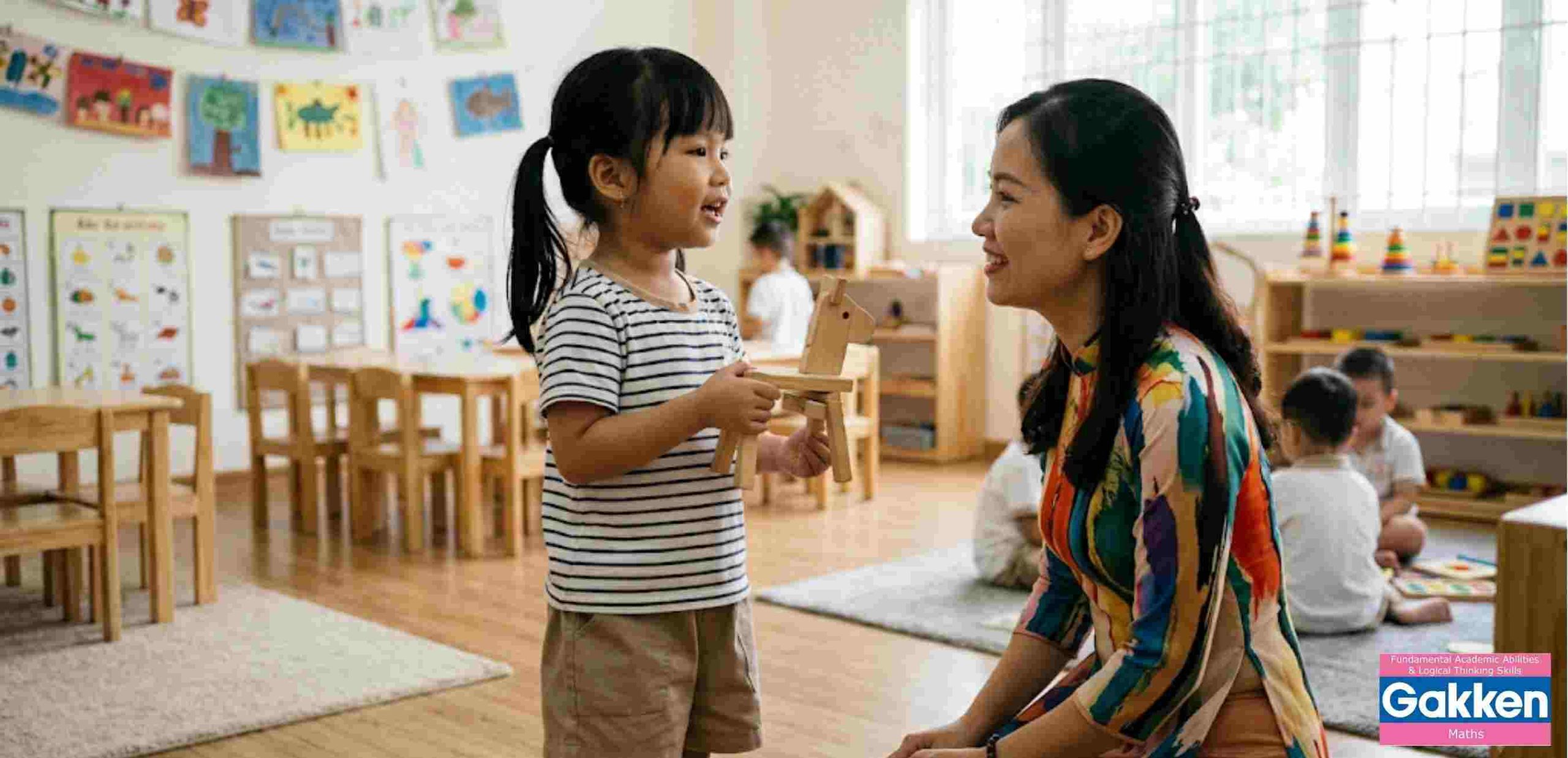 Một bé gái cầm đồ chơi ngựa gỗ đang say sưa trò chuyện cùng cô giáo mầm non trong lớp học. Cô giáo quỳ gối ngang tầm mắt trẻ, mỉm cười ấm áp và chăm chú lắng nghe. Hình ảnh thể hiện sự giao tiếp tích cực, hướng dẫn trẻ cách diễn đạt và tự giải quyết tình huống.