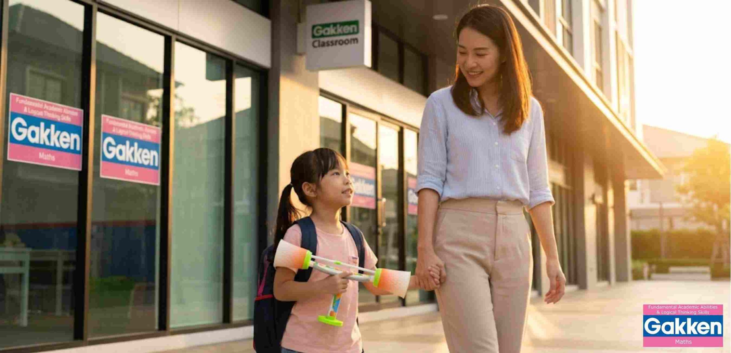 Mẹ dắt bé gái đeo ba lô đến lớp học, cùng mang theo đồ chơi giáo dục, thể hiện sự đầu tư cho việc học tập và phát triển kỹ năng của trẻ.